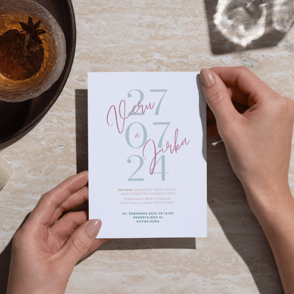 osoba drží v ruce svatební pozvánku